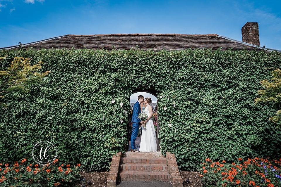 Bride and Groom in archway kissing